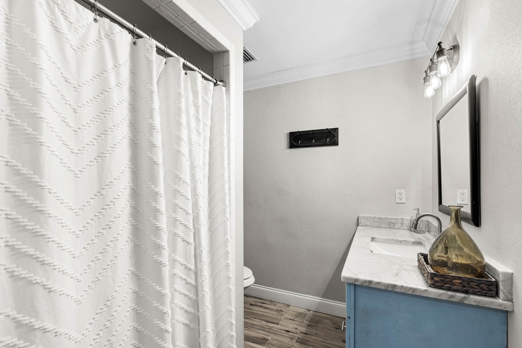 bathroom with blue sink cabinet and white shower curtain